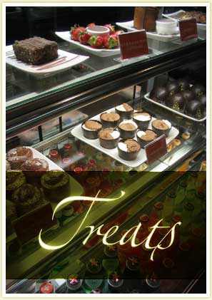 image shows a display case full of treats: cakes, tarts, cold drinks, pies etc.